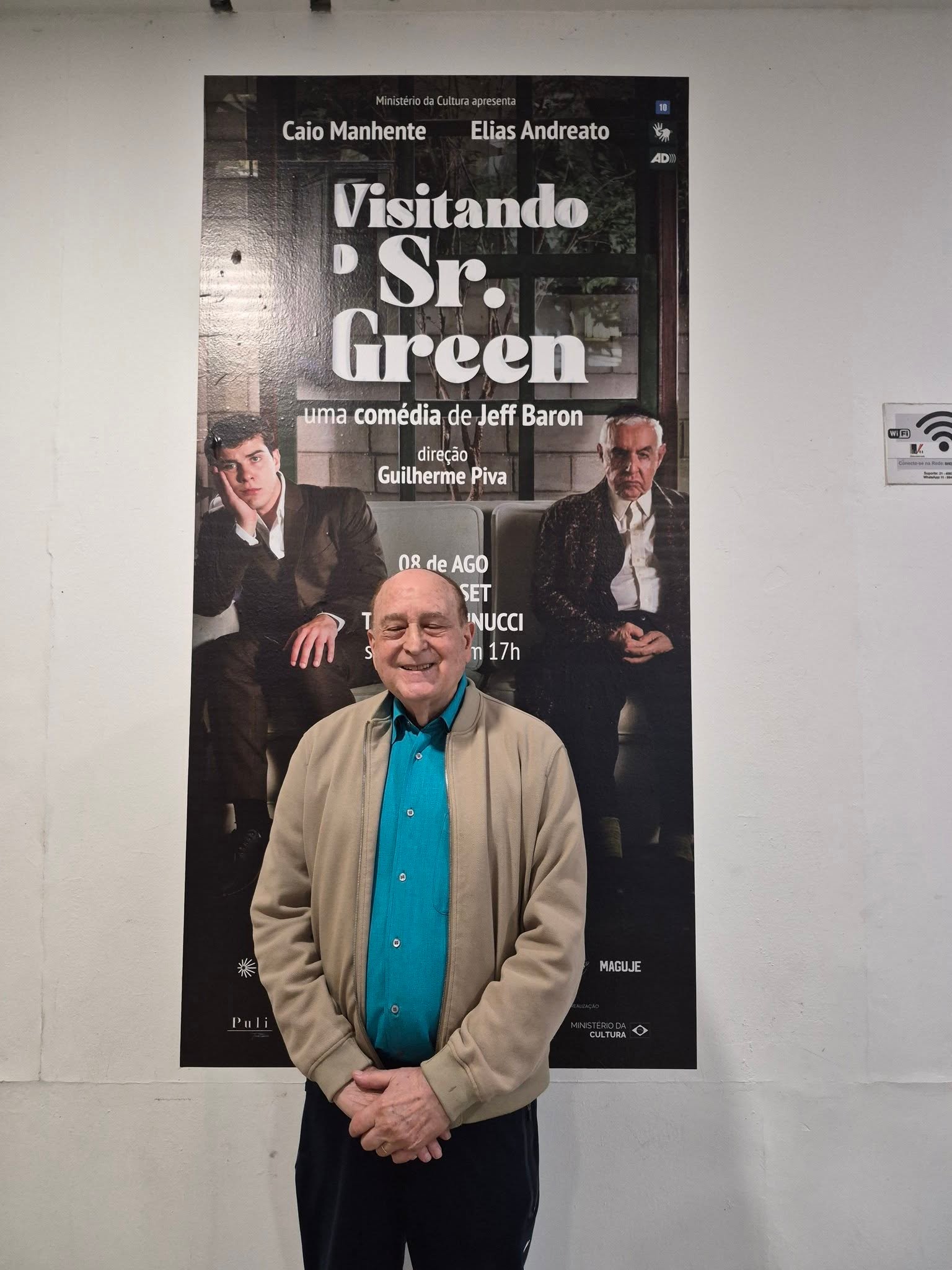 Harold Emert diante de um cartaz de Visitando o Sr. Green no Teatro Vannucci